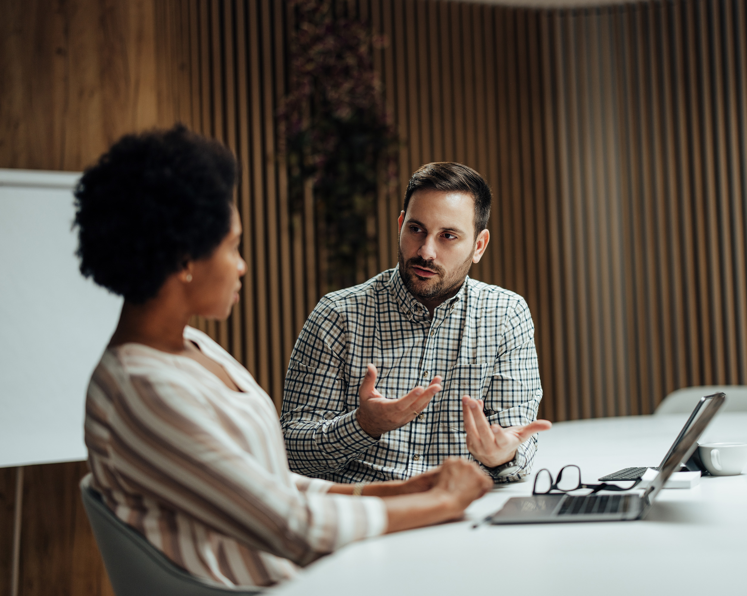 A male and female in a meeting discussing the key benefits of outsourcing HR